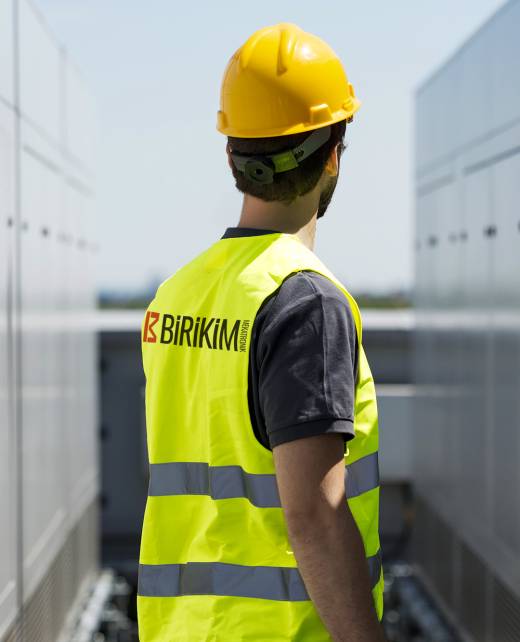 Construction worker, wearing hard hat and hi vis vest, outdoors, rear view